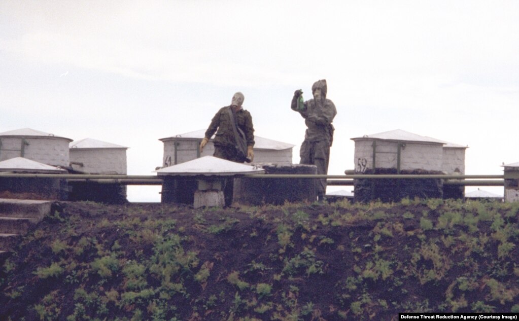 Dy persona të paidentifikuar me pajisje mbrojtëse në një vend të prodhimit të armëve të shkatërrimit në masë, në Ukrainë, më 1996.