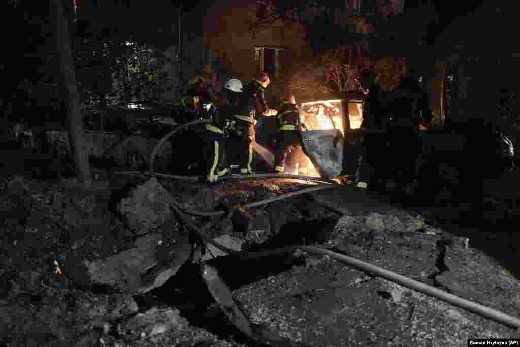 Az orosz dróncsapásból származó leeső törmelék könnyen okoz tüzet. A képen egy kigyulladt autót oltanak Kijev Pecserszkij kerületében
