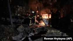 Рятувальники гасять автомобіль, який загорівся через падіння уламка збитого дрона, Київ, 30 травня 2023 року