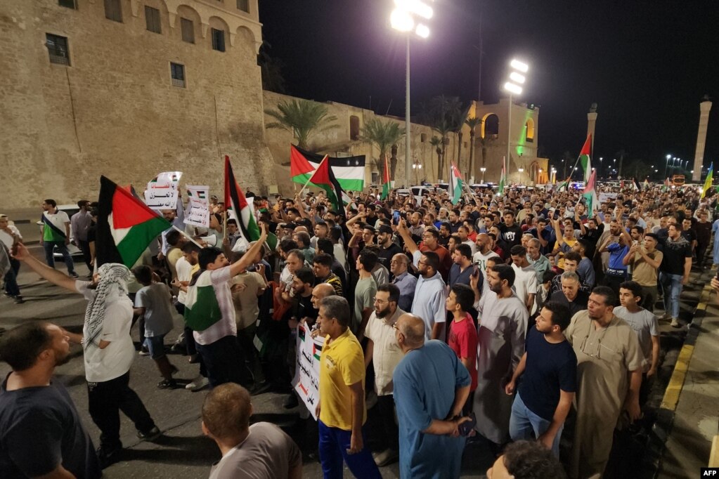 Njerëzit mbajnë pankarta dhe flamuj palestinezë gjatë një proteste në kryeqytetin e Libisë, Tripoli, vonë më 17 tetor 2023, në mbështetje të palestinezëve pas një sulmi që shpërtheu në spitalin Ahli Arab në Gazën qendrore, i cili vrau qindra persona.