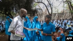  Абдулахи Мире раздава книги на ученици-бежанци в бежанския лагер Дадааб в Кения. 