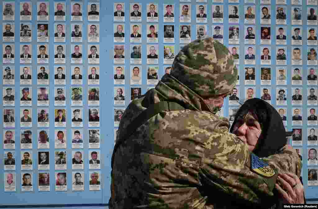 A Ukrainian soldier embraces a woman who was paying her respects.