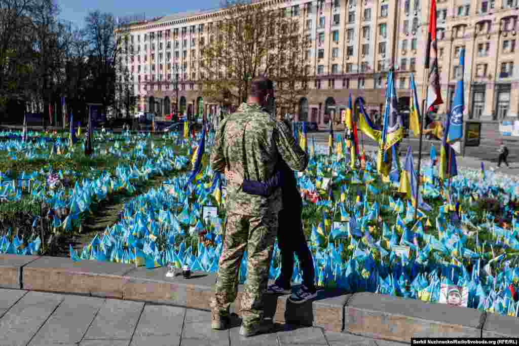 Батько з сином вшановують пам&#39;ять загиблих оборонців України. Синьо-жовті прапорці на Майдані Незалежності символізують&nbsp; полеглих захисників. Київ, квітень 2024 року