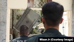 Police officers tear down the DSIT's signboard in Tehran on August 20.