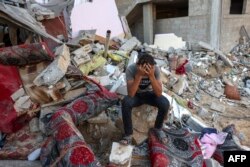 Палестинский юноша сидит на развалинах разрушенного дома после израильского военного удара по лагерю беженцев в Рафахе на юге сектора Газа, 15 октября 2023 года