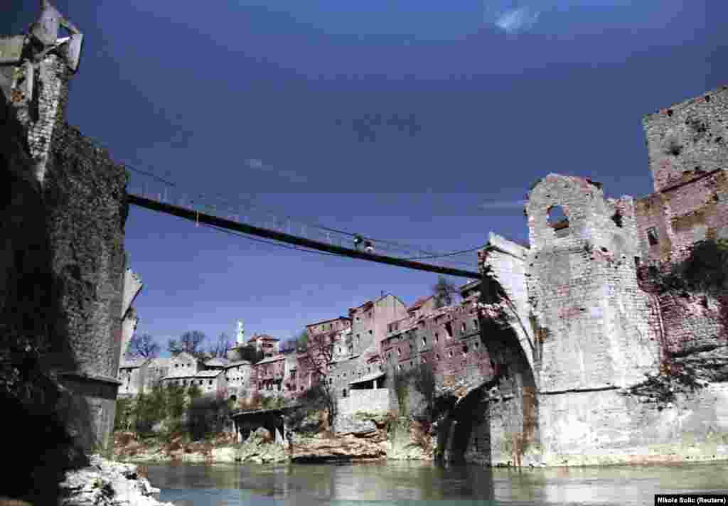 Жители на Мостар минават през временен пешеходен мост над река Неретва през март 1994 г. В годините след войната на мястото на разрушеното старо съоръжение през реката са прекарани различни временни мостове.