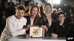 Жюстин Трие (втората вляво) позира с френския актьор Антоан Рейнарц, Сандра Хюлер и Мило Мачадо Гранер, който играе ролята на момчето във филма, след получаването на "Златна палма" в Кан, през май 2023 г.