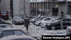 A Ukrainian police officer walks in front of a multistory apartment building, which was damaged during a Russian air attack on Kyiv on May 30.