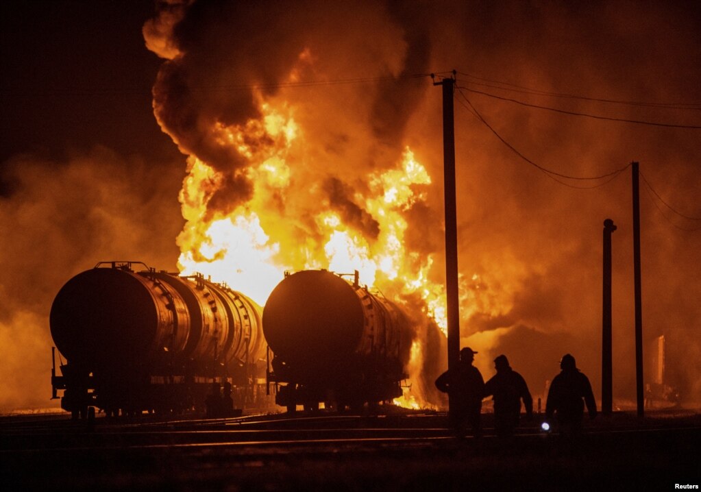 Banorët vendas shikojnë vagonët e trenave të djegur pas granatimeve në një kryqëzim hekurudhor në Donjeck. ​