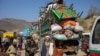Trucks loaded with goods arrive as Afghan nationals head back to Afghanistan at the Torkham border crossing between Pakistan and Afghanistan on October 30.
