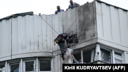 Специалисты осматривают повреждённый фасад многоэтажного жилого дома после атаки беспилотника в Москве 30 мая 2023 г.