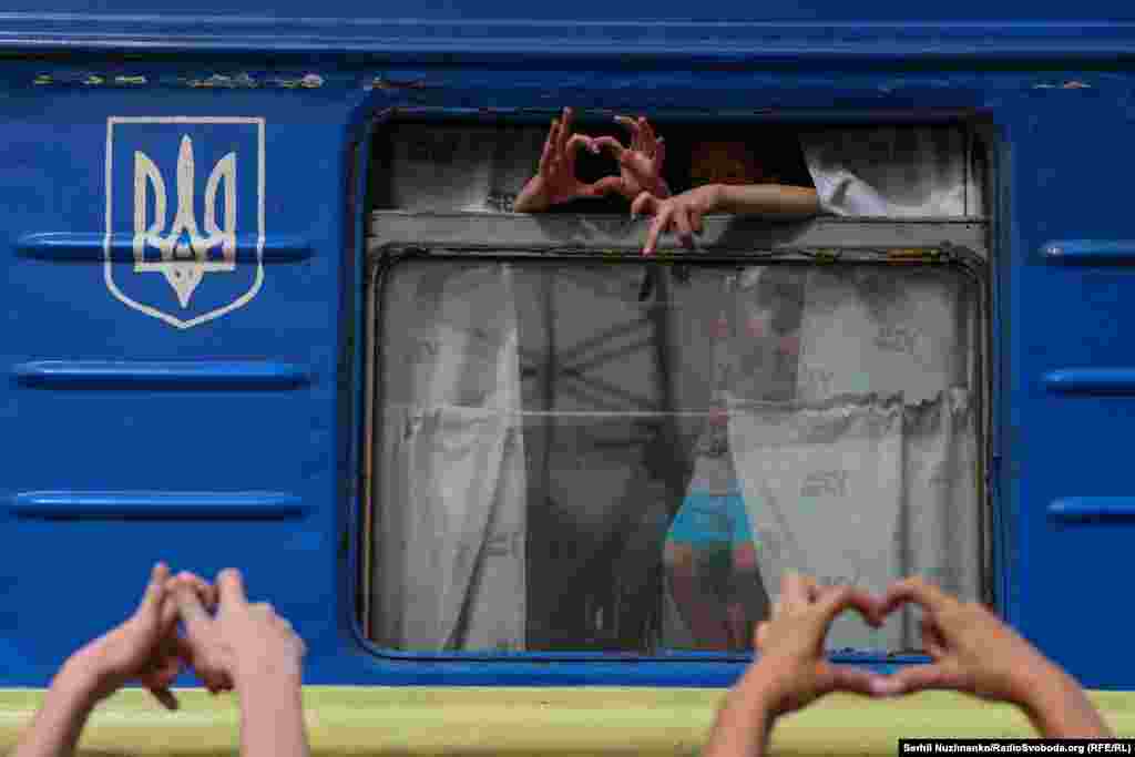 Family members and friends make the heart symbol as the evacuation train begins its departure from the platform. &nbsp;