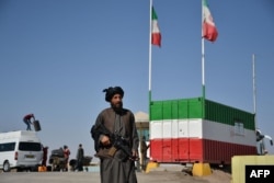 A Taliban fighter stands guard at the border between Iran and Afghanistan.