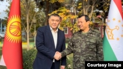 Kyrgyz security chief Kamchybek Tashiev (left) and his Tajik counterpart, Saimumin Yatimov, shake hands earlier this month. 