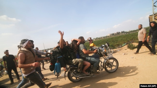 Палестинці перевозять захопленого ізраїльського цивільного (в центрі) з кібуцу Кфар-Аза в сектор Гази. 7 жовтня 2023 року