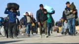 Afghan immigrants deported back from Iran carry their belongings at a registration center in the Islam Qala border town of the western Herat Province. (file photo)