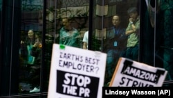 Az Amazon munkatársai figyelik, hogy más Amazon-dolgozók az irodáik előtt tüntetnek Seattle-ben 2023. május 31-én