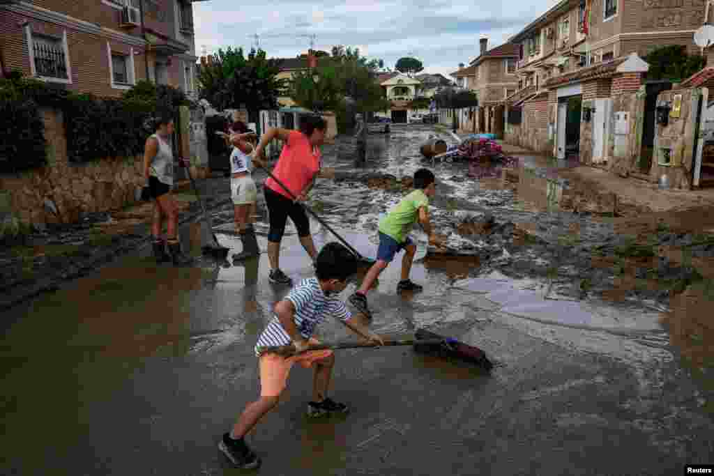 Carmen Palomino dhe djemtë e saj Mario, 8 vjeç dhe Alex, 6 vjeç, ndihmojnë fqinjët për të hequr baltën pas shirave të dendur në Villamanta, Spanjë, 6 shtator 2023.