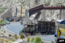 Residents stand beside a charred vehicle near a collapsed railway bridge the morning after a blast caused by separatist militants in Kolpur in the Bolan district of Balochistan Province in August.