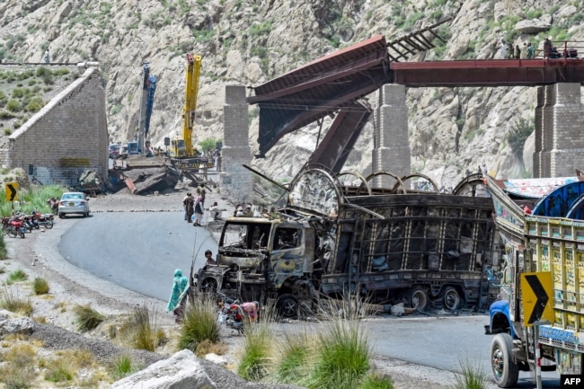 Residents stand beside a charred vehicle near a collapsed railway bridge the morning after a blast caused by separatist militants in Kolpur in the Bolan district of Balochistan Province in August.