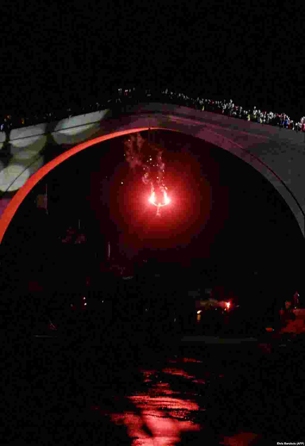 A young Mostar local leaps from the rebuilt bridge while holding flares on the reopening ceremony on July 23, 2004. After years of lobbying to get the bridge rebuilt, Pasic said he felt &quot;very emotional and very tired&quot; during the 2004 reopening. &quot;In the middle of the ceremony, when everything was going well, I could relax. At that moment, I was free,&quot; he said. &nbsp;