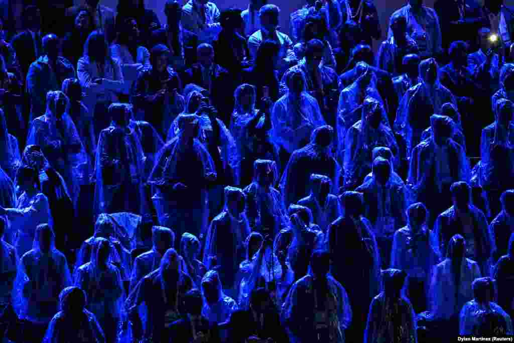 Njerëz të veshur me veshje mbrojtëse nga shiu gjatë ceremonisë së hapjes së Lojërave Olimpike në Paris.