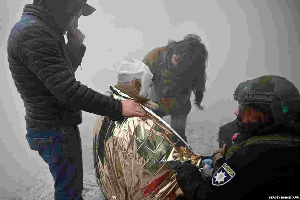 Ukrainian law enforcement officers provide assistance to a local resident injured as a result of a missile attack on Kharkiv.&nbsp;