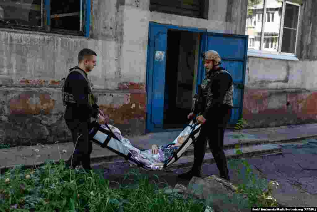 Волонтери виносять літню жінку в ношах