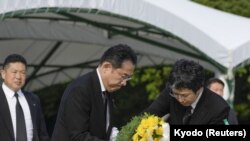 Premierul Japoniei, Fumio Kishida (în stânga) în timpul ceremoniei de depunere de coroane de flori, la evenimentul de comemorare a victimelor de la Hiroshima.