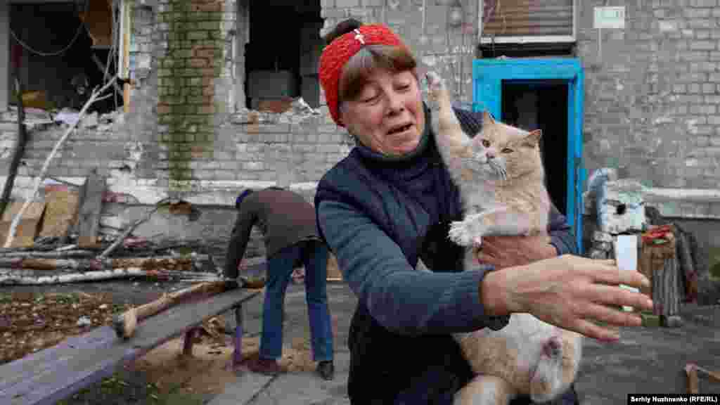 Местната жителка Рита държи котка, докато нейната съседка Раиса реже дърва. Малкото останали цивилни в Авдиивка търсят убежища от постоянните обстрели&nbsp;в мазетата на разрушените сгради.&nbsp;