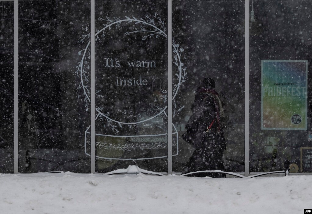 Një person duke ecur në një trotuar të mbuluar me borë në lagjen East Village, të Des Moines, Ajova. 