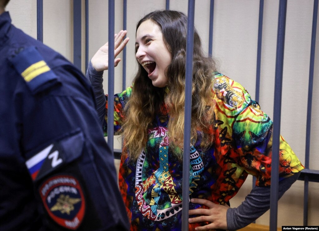 Sasha Skochilenko, një artiste dhe muzikante 33-vjeçare e akuzuar për përhapjen e informacionit të rremë në lidhje me forcat e armatosura të Rusisë pasi zëvendësoi etiketat e çmimeve të supermarketeve me slogane që protestojnë kundër pushtimit të Ukrainës, reagon brenda grilave për të pandehurit gjatë një seance gjyqësore në Shën Petersburg. Rusia, më 8 nëntor.