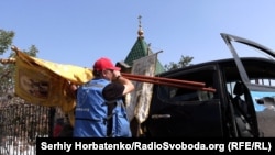 Євген Ткачов завантажує до пікапа церковні хоругви...