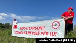 „Не заминувај, и требаш на твојата татковина“, пишува на транспарент истакнат за време на протестот за Меѓународниот ден на трудот во Тирана на 1 мај 2024 година.