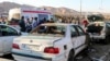 Disa njerëz qëndrojnë pranë makinave të shkatërruara pas një shpërthimi në Kerman. Iran, 3 janar 2024. 