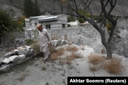 Султан Али (70) поминува низ пукнатините што се создадоа откако излевање на глацијално езеро однесе дел од земјата во Хасанабад.