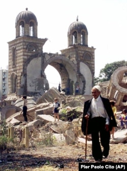 A Kosovar man walks in front of the ruins of an Orthodox Serbian church in Gjakova, western Kosovo in July 1999 after an explosion destroyed the building. No trace of the church remains today.