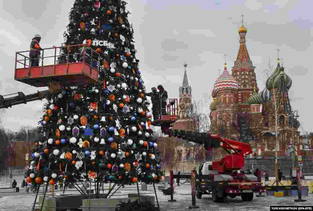 Workers install decorations on a festive tree for the New Year and Christmas season near the Kremlin in Moscow, Russia.&nbsp;