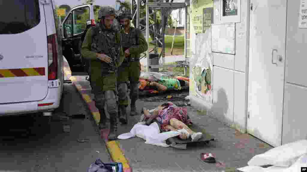 Izraeli katonák a palesztin fegyveresek által kivégzett civilek holttestei mellett az izraeli Szderótban 2023. október 7-én