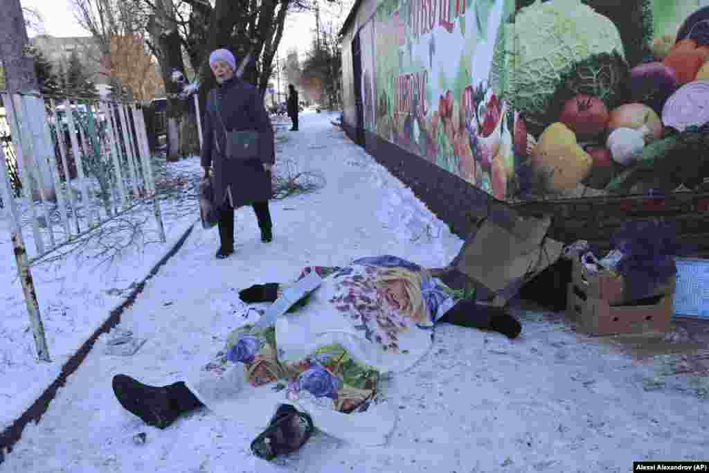 A woman walks past the body of a victim killed during shelling in Donetsk in the Russian-controlled region of eastern Ukraine.