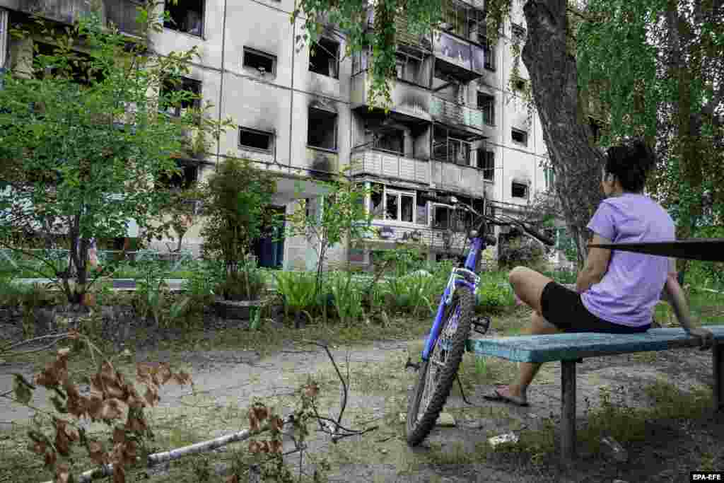 A woman sits in front of a damaged residential building in Shebekino, Belgorod region, Russia.