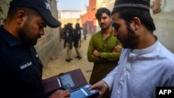 په کراچۍ کې یو افغان کډوال پولیسو ته د خپل بایومېټرېک معلوماتو ورکولو پر مهال ګوته لګوي - د نومبر ۱۷مې انځور.