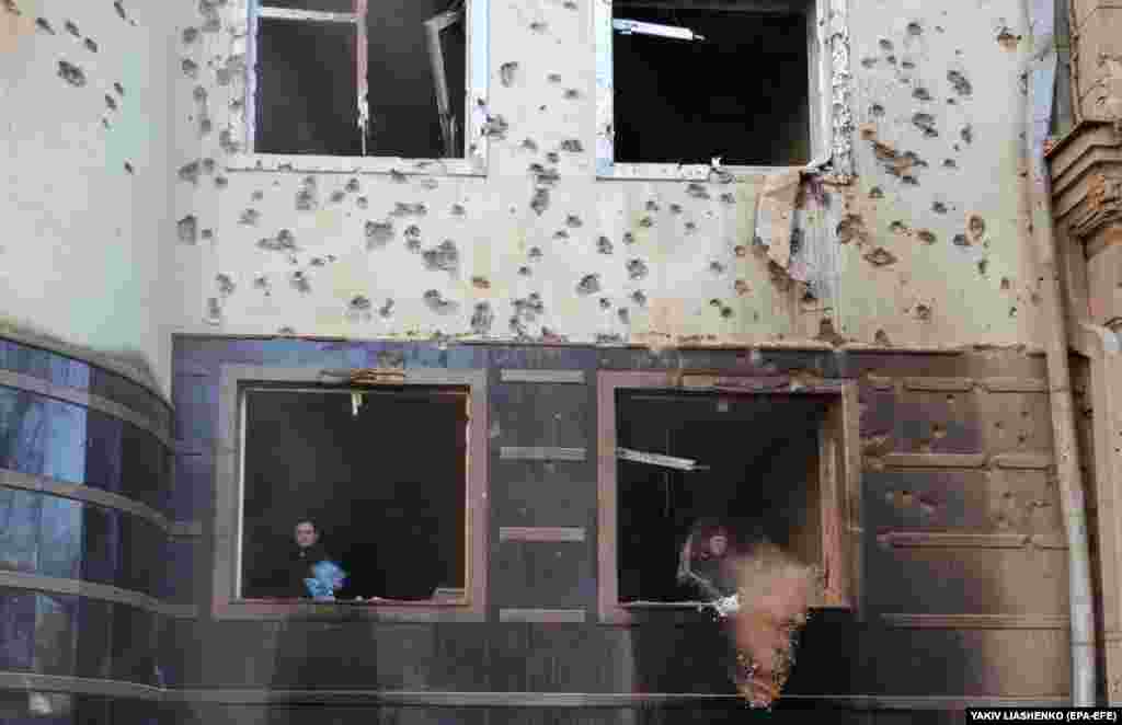 People clean debris at the site of an overnight Russian rocket attack in Kharkiv, Ukraine.