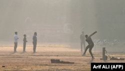 Youths play cricket amid smoggy conditions in Lahore on November 14. 