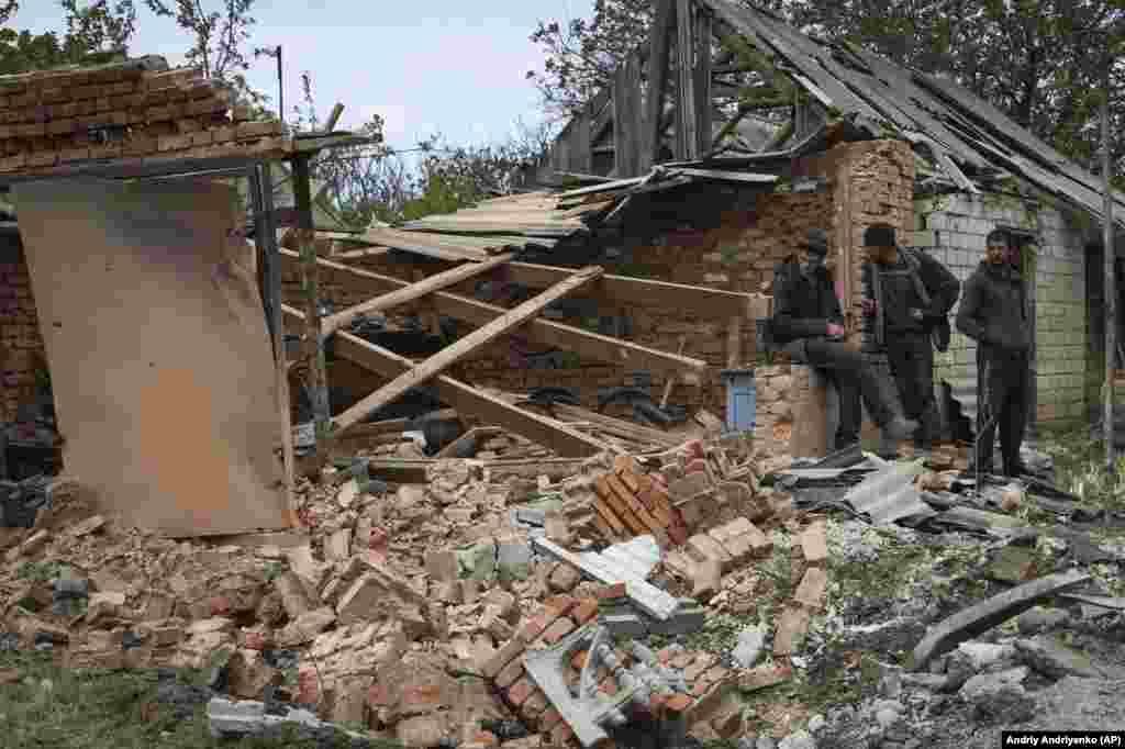 Stanovnici stoje pored zgrade oštećene ruskim granatiranjem u Komiševaki, region Zaporožja, 8. maja.