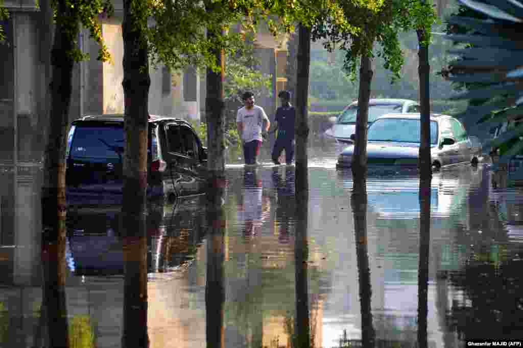 People wade through a flooded street after heavy rainfall in Faisalabad, Pakistan.