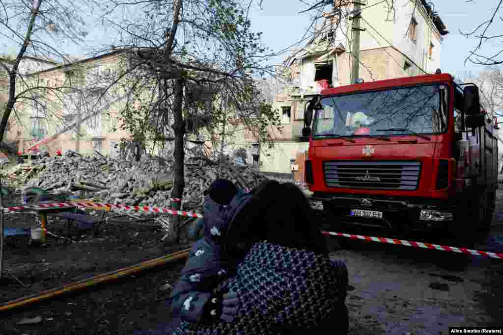 Žena i dete gledaju uništenu stambenu zgradu. Ukrajinsko tužilaštvo saopštilo je na svom Telegram kanalu da su ruske trupe protivvazdušnim sistemom S-300 lansirale četiri rakete na taj grad, pogodivši četvorospratnicu.