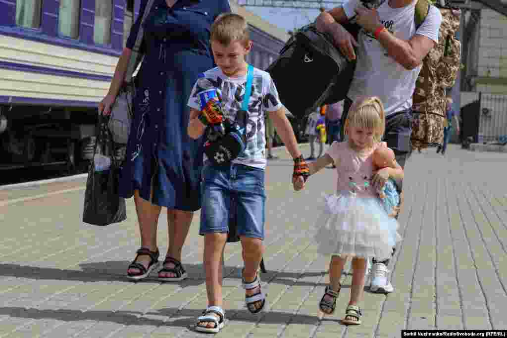 Ilya, aged 7, and his sister Valeriya, aged 3, walk along the train platform with their parents. Originally from Donetsk, the family was forced to evacuate from their home for the third time.