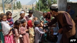 An Afghan health worker administers polio vaccine drops to children during a polio vaccination campaign in Kandahar.