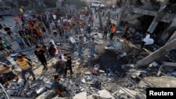 Palestinezët duke shikuar për viktima nën rrënojat e një ndërtese të shkatërruar nga sulmet ajrore izraelite në Rripin e Gazës.